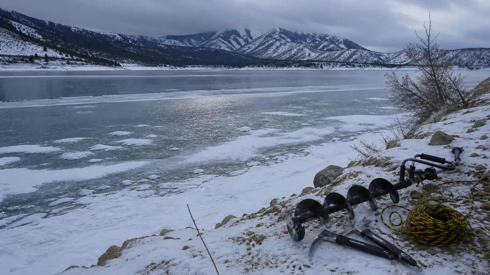 Frozen reservoir with fishing equipment on snowy shore