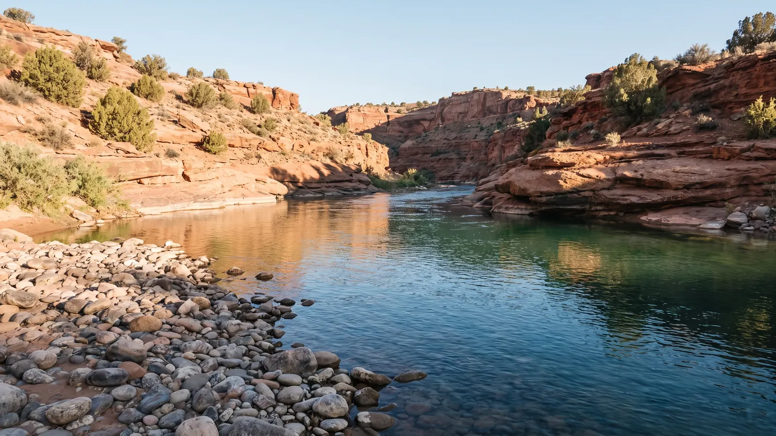 Clear river water beneath layered sandstone canyon walls