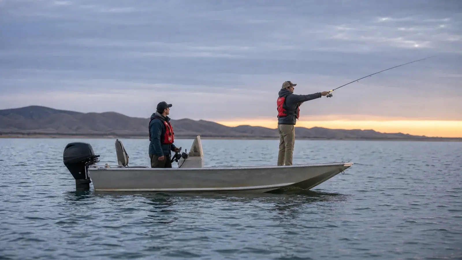 Two anglers wearing life jackets fishing from an aluminum boat